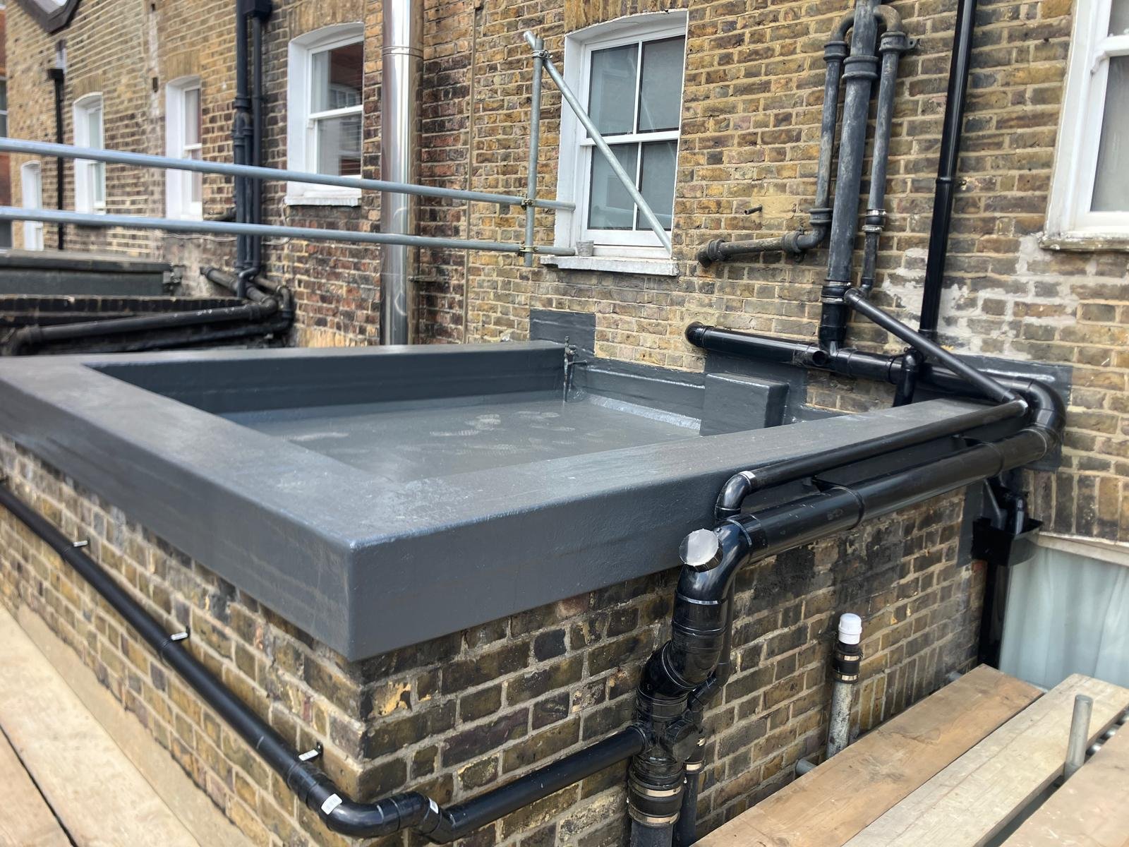 Flat roof replacement: completed flat roof with waterproofed perimeter upstands and brick wall junctions