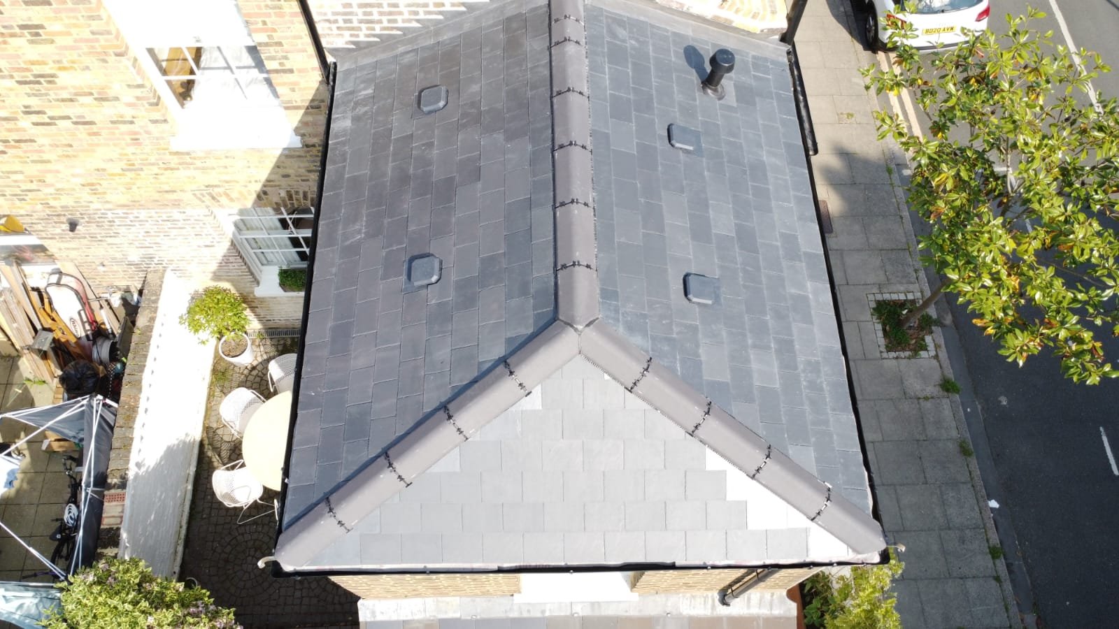 Slate roofing: completed natural slate pitched roof with ridge and roof junction detailing